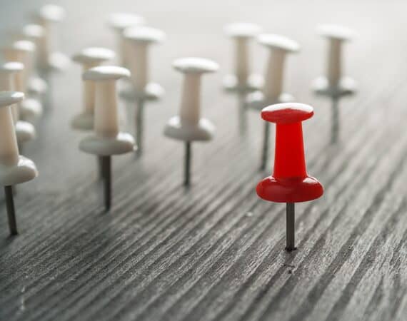 A red pushpin standing out against many white pushpins, representing distinctive competencies.